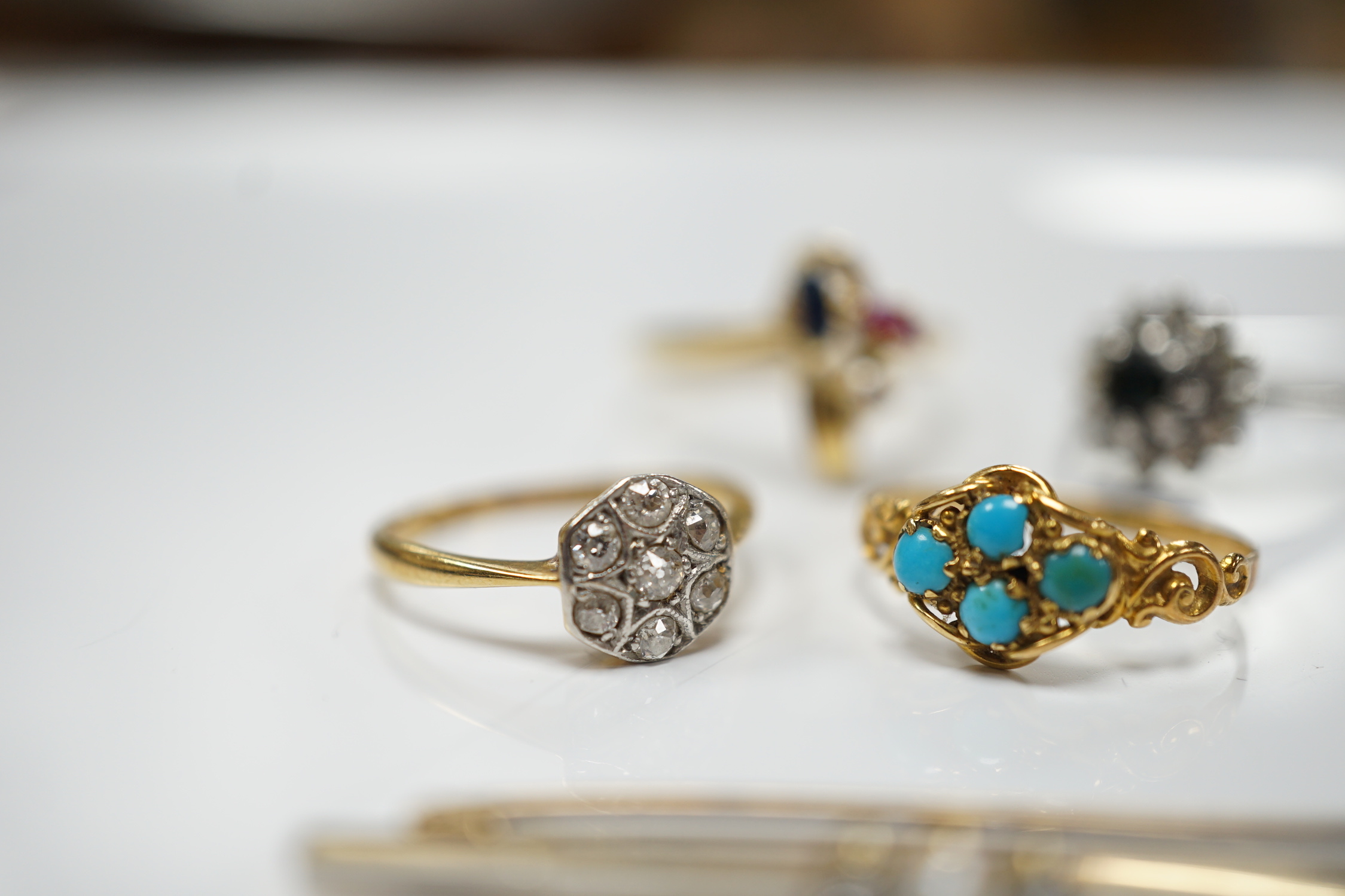 Three assorted 18ct and gem set rings, including 1920's diamond cluster, size K/L, one other early 20th century yellow metal and turquoise cluster set ring and a 15ct, diamond and seed pearl set three stone bar brooch.